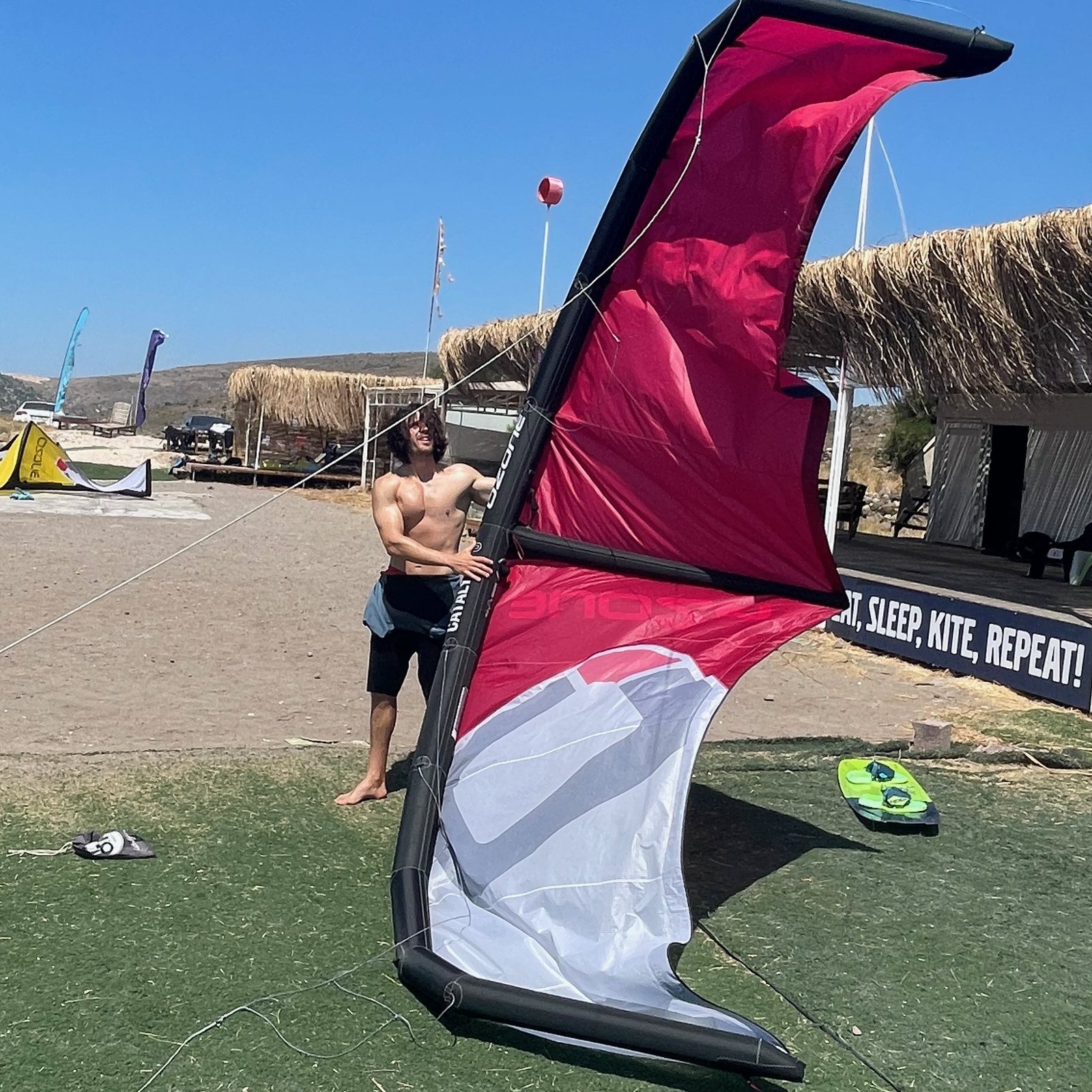 Adem Gün holding a kitesurfing wing on the beach