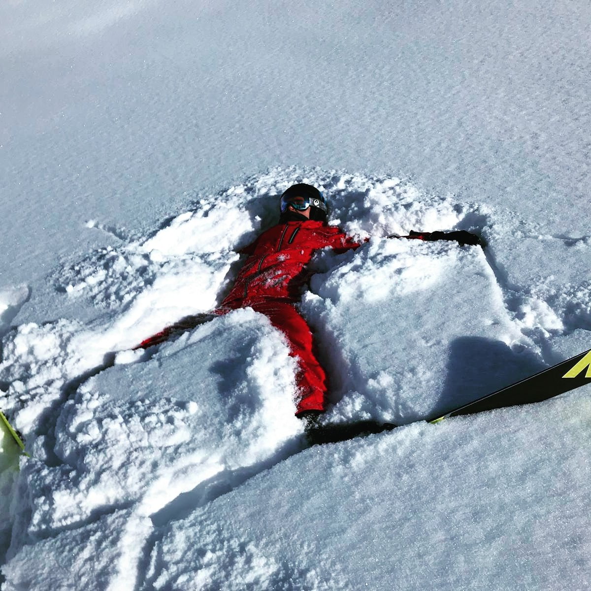 Adem Gün lying in fresh snow on skis